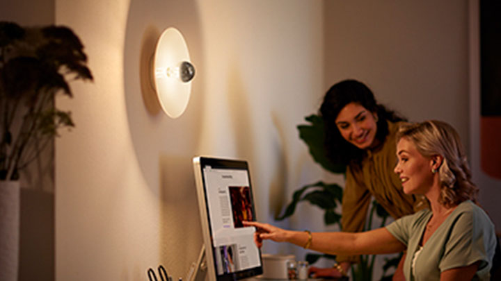 Women working on the computer next to a wall mounted Philips LED mirror bulb
